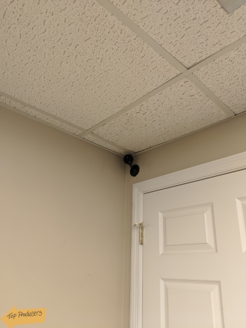 Indoor security camera mounted near the ceiling above a doorway